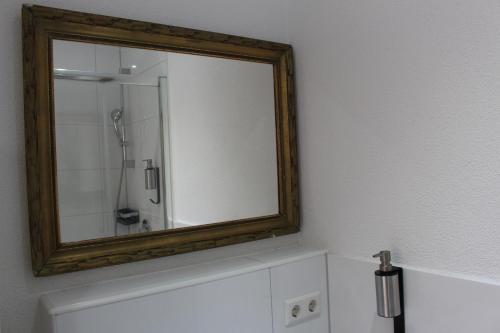 a mirror on a wall above a bathroom sink at Looks Inn in Heidelberg