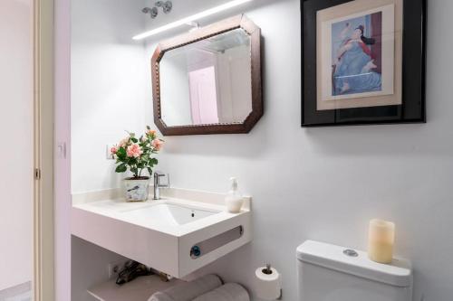 łazienka z białą umywalką i lustrem w obiekcie Apartamentos RG, San Vicente 22 w Sewilli