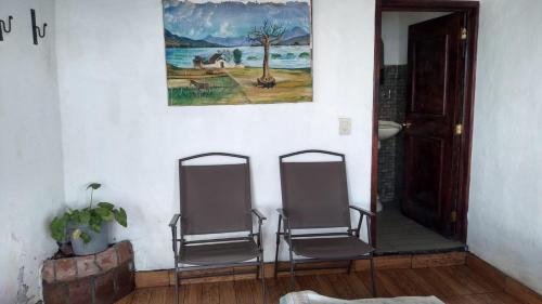 two chairs in a room with a picture on the wall at Cabaña Aurora in Zirahuén
