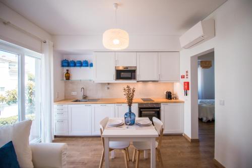 a kitchen with white cabinets and a table with chairs at 188 Apartments - Petúnia - Pool and Balcony in Cascais