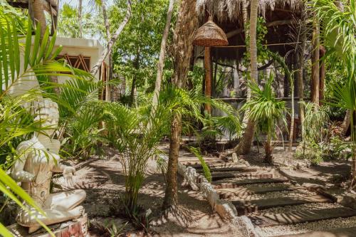 un jardin avec des palmiers et un bâtiment dans l'établissement Yaxchen Tulum Cabañas & Cenote, à Tulum