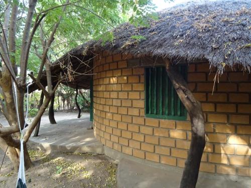 a brick building with a grass roof and a window at Kansala Ta Toto in Kafountine