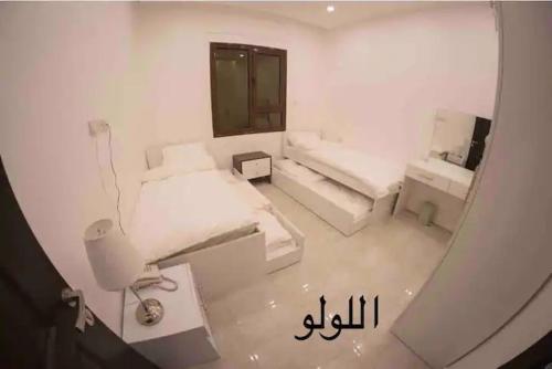 a white room with two beds and a mirror at منتجع اووه يامال البحري في الخيران OOh Yaa Mal in Al Khīrān