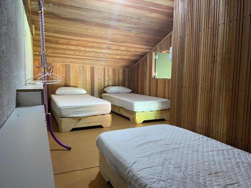 a room with three beds in a wooden room at Hostel Raizer in Campo Grande