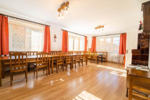 jadalnia z pomarańczowymi zasłonami oraz drewnianymi stołami i krzesłami w obiekcie Holiday house Vedle w mieście Desná