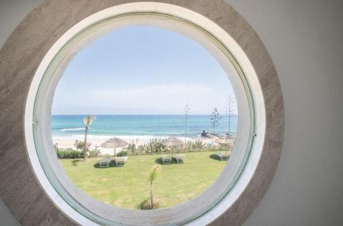 a round window with a view of the beach at Villa Escargot Luxury in Costa Rei Beach in Costa Rei