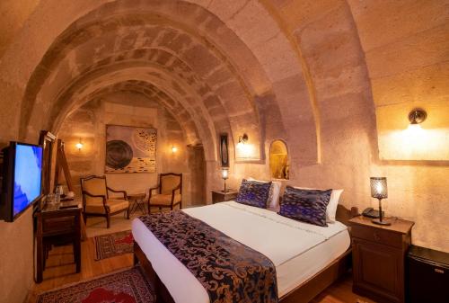 a hotel room with a bed and a desk and a television at Portal Cappadocia Hotel in Ortahisar