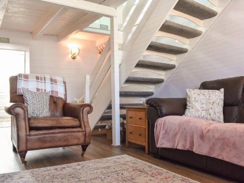 a living room with two chairs and a staircase at Bay Cottage in Cayton