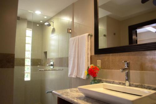 y baño con lavabo y espejo. en Placencia Pointe Townhomes #7, en Placencia Village