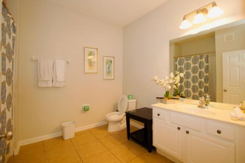 a bathroom with a sink and a toilet and a mirror at Vista Cay Standard 2 bedroom condo (#3102) in Orlando