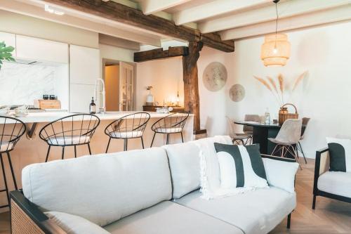 a living room with a white couch and a kitchen at Monumentale stolpboerderij voorzien van alle gemakken van nu! in Twisk