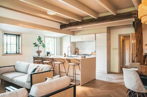 een woonkamer met een bank en een keuken bij Monumentale stolpboerderij voorzien van alle gemakken van nu! in Twisk
