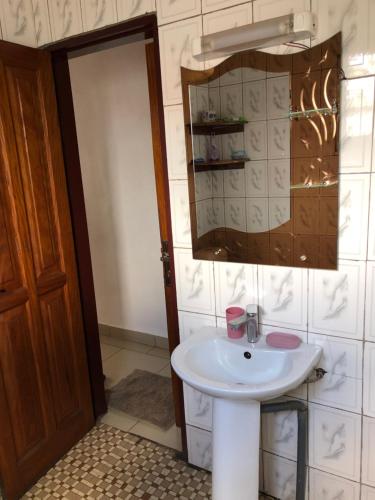 a bathroom with a white sink and a mirror at Grand Appartement à essos mobile in Yaoundé