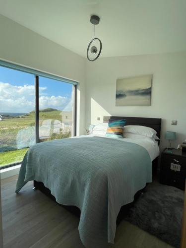 a bedroom with a large bed and a large window at Flora's Cliff View in Kilmuir