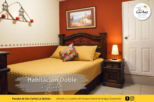 a bedroom with a bed with an orange wall at Posada de San Carlos La Quinta in Antigua Guatemala