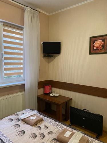 a bedroom with a bed and a table and a television at Відпочинковий комплекс,міні готель Старий дворик in Lviv