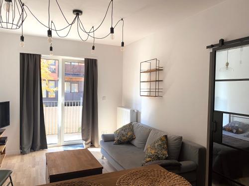 a living room with a couch and a chandelier at Project Comfort Apartament Klasyków 10A/7 Warszawa in Warsaw