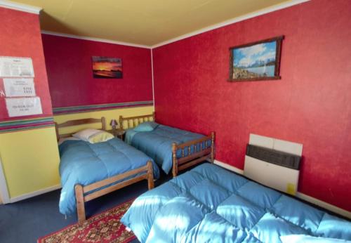 two beds in a room with red walls at Hospedaje Independencia y camping in Punta Arenas