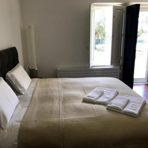 a bed with two towels on it with a window at Villa das Oliveiras in Sintra