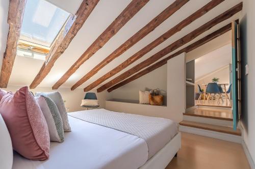 マドリードにあるApartamentos Fucarの白いベッドと木製の梁が備わるベッドルーム1室