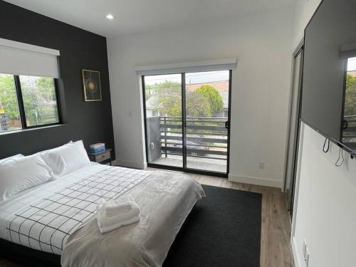 a bedroom with a white bed and a large window at Delightful Town Home close to DTLA in Los Angeles