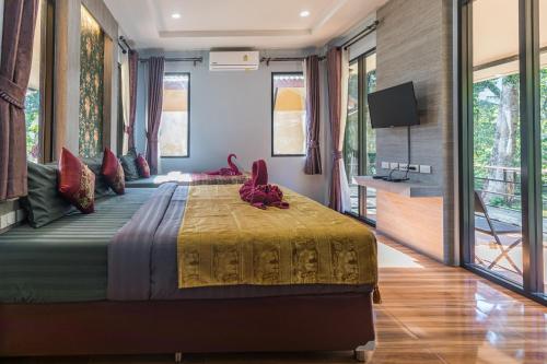 a bedroom with a large bed with a television and windows at Khaosok Rainforest Resort in Khao Sok