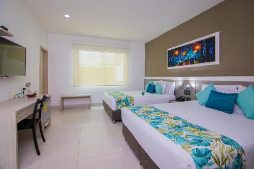a hotel room with two beds and a desk at Varanasi Hotel Boutique Aeropuerto in Cartagena de Indias
