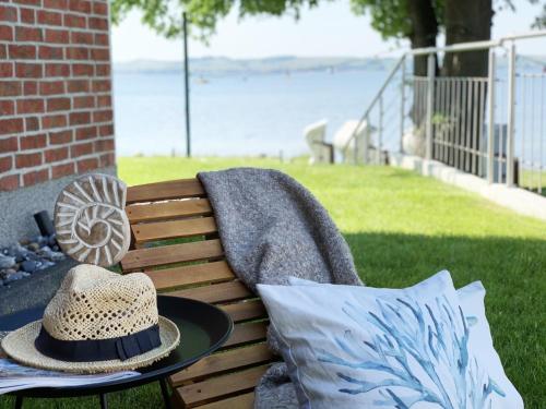 a hat sitting on a bench near the water at Chalet Möwenblick Rügen mit Meerblick, Sauna und Kamin in Alt Reddevitz