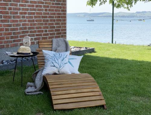 a wooden chair with pillows sitting next to a table at Chalet Möwenblick Rügen mit Meerblick, Sauna und Kamin in Alt Reddevitz