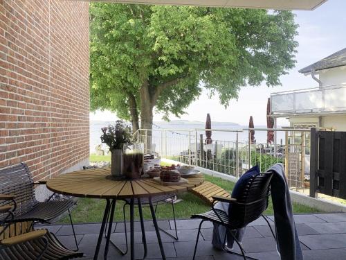 a table and chairs on a patio with a tree at Chalet Möwenblick Rügen mit Meerblick, Sauna und Kamin in Alt Reddevitz