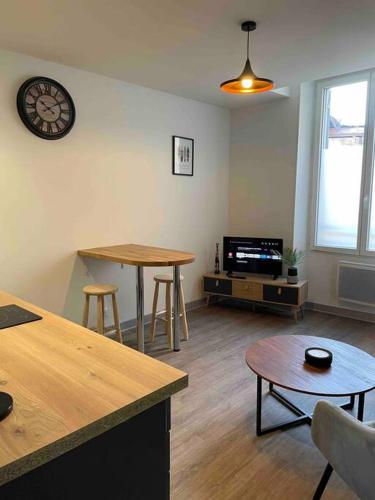 a living room with a table and a clock on the wall at T2 face gare SNCF Appart Hotel le Cygne 1 in Bourges