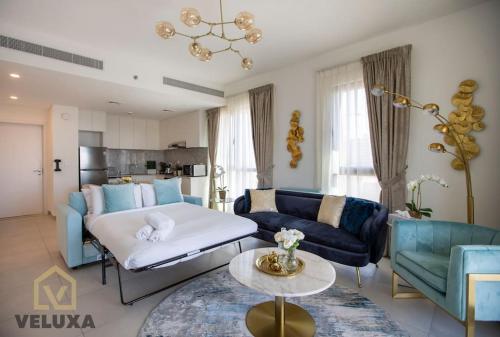 Veluxa - Luxury and bright 1 bedroom apartment, Burj view! في دبي: غرفة معيشة فيها أريكة وطاولة فيها
