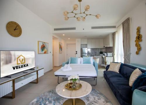 un soggiorno con un divano blu e un letto di Veluxa - Luxury and bright 1 bedroom apartment, Burj view! a Dubai