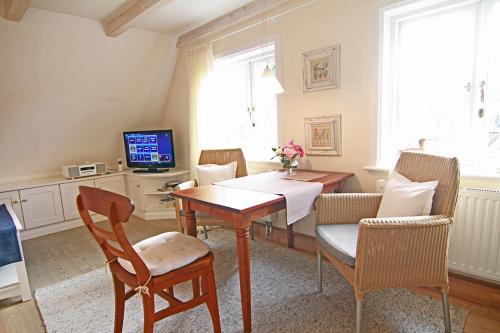 a dining room with a table and chairs and a television at App Anne in Westerland (Sylt)