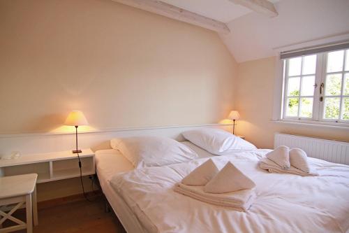 una camera da letto con un letto bianco e asciugamani di App Anne a Süderende