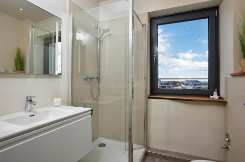 ein Bad mit einer Dusche, einem Waschbecken und einem Fenster in der Unterkunft App WolkenLoft in Westerland