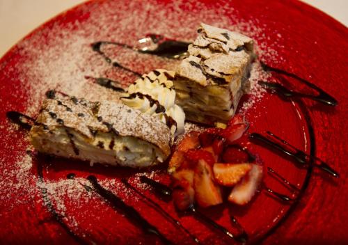 a red plate with two pieces of cake and fruit at Panoramagasthof auf dem Auerberg in Bernbeuren