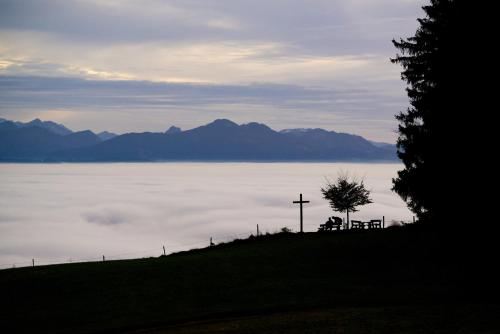 a cross on a hill with a view of a body of water at Panoramagasthof auf dem Auerberg in Bernbeuren