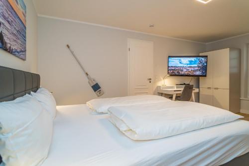 Schlafzimmer mit einem weißen Bett und einem TV an der Wand in der Unterkunft Sylt Oase in Westerland
