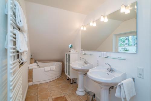 a bathroom with two sinks and a tub and a mirror at Söns Hüs in Munkmarsch