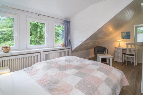 a bedroom with a bed and a desk and windows at Söns Hüs in Munkmarsch