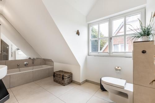 a white bathroom with a sink and a bath tub at Anker Hus in Westerland