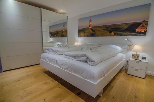 a bedroom with a white bed with a painting on the wall at Hoogen Hüs in Westerland