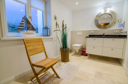 a bathroom with a chair and a boat in a window at Hoogen Hüs in Westerland