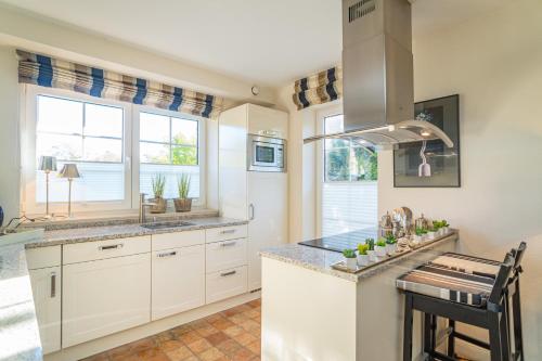 a kitchen with white cabinets and a counter top at Maarwiet Hüs in Wenningstedt