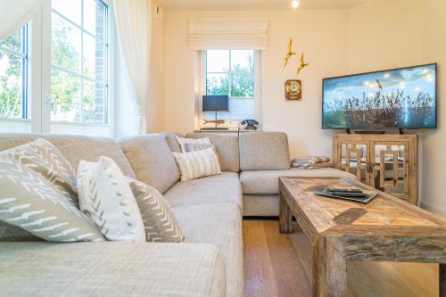 a living room with a couch and a tv at Maarwiet Hüs in Wenningstedt