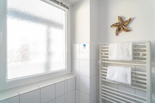 ein weißes Bad mit einem Fenster und einem Seestern an der Wand in der Unterkunft Seestern in Westerland