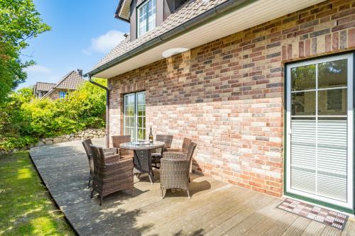 a patio with chairs and a table and a brick wall at Maarwiet Hüs in Wenningstedt