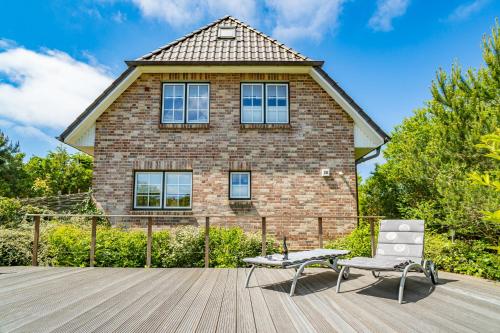 a house with a bench and a chair on a deck at Maarwiet Hüs in Wenningstedt