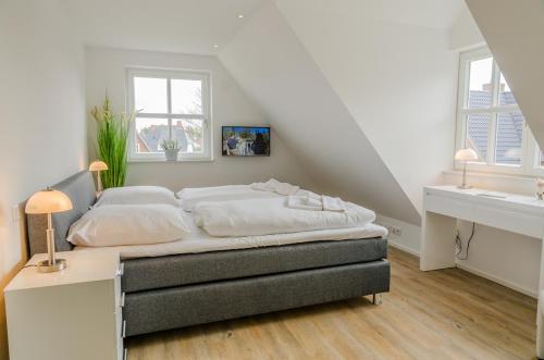 - une chambre avec un lit doté de draps blancs et 2 fenêtres dans l'établissement Wandafül Hüs, à Westerland